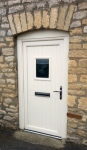 Secure composite front door by Apeer, installed by Cliffside Windows in Lincolnshire. Cream front door in a stone wall with glazed window.